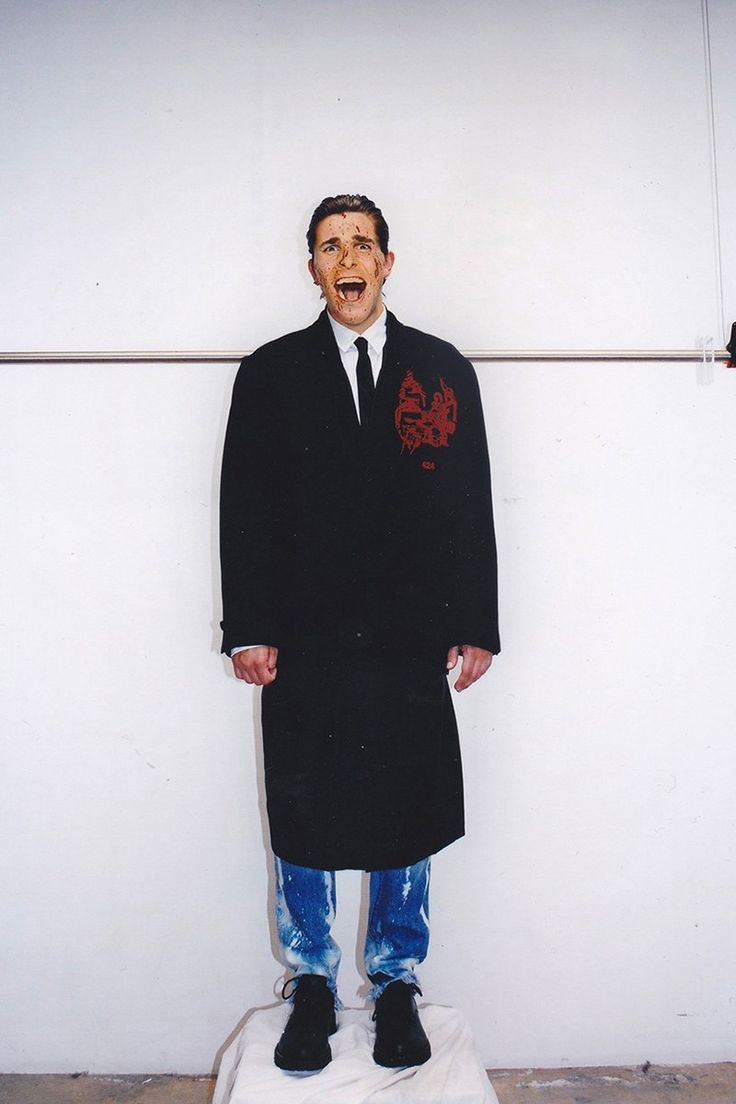 a man in a suit and tie standing on top of a white object with his mouth open