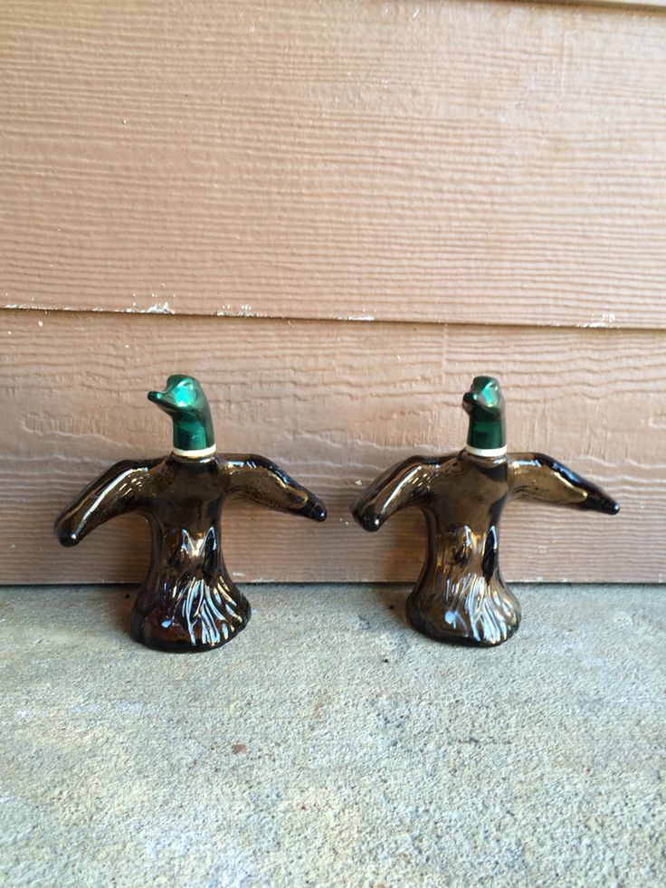 two ceramic ducks sitting next to each other on the ground in front of a door