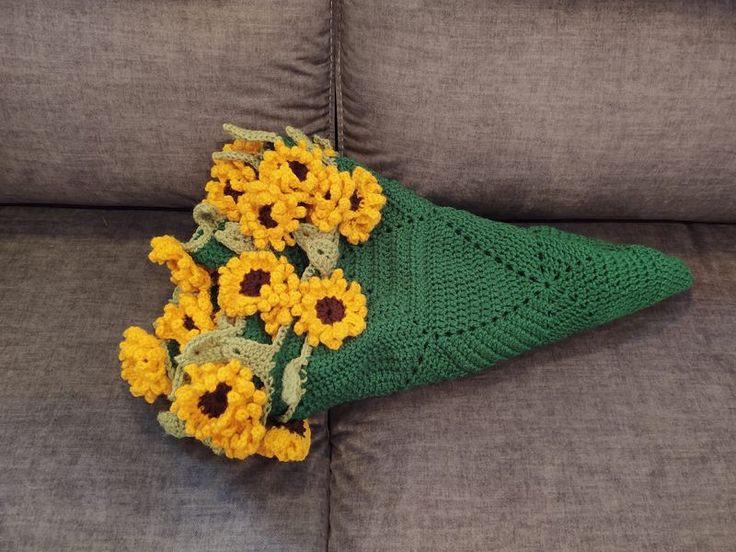 a green crocheted hat with sunflowers on it sitting on a couch