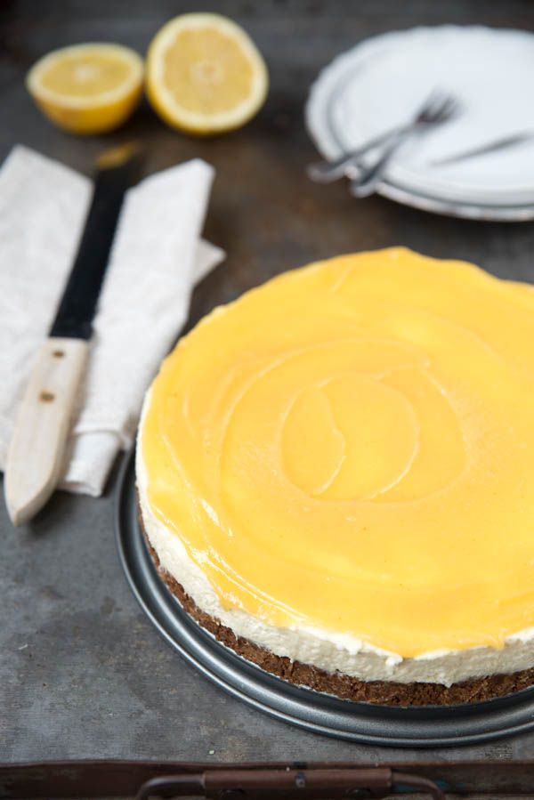 there is a cake with yellow icing on the plate next to utensils