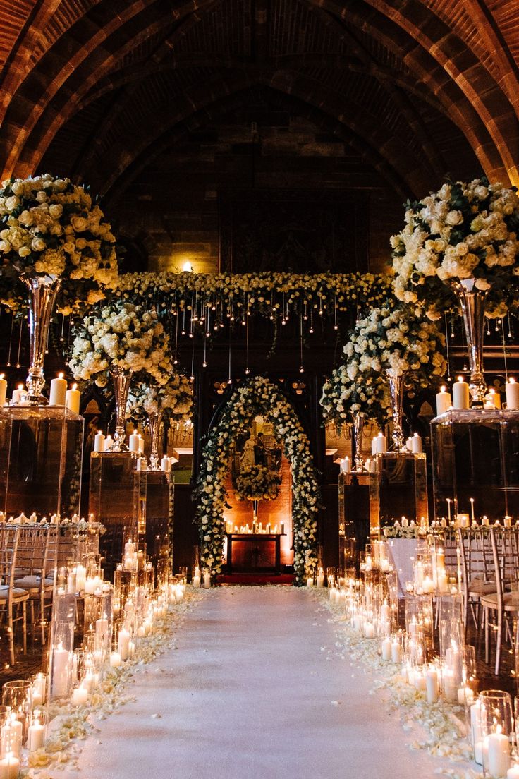 the aisle is lined with candles and flowers for an elegant wedding ceremony at night time