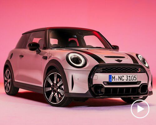 the front end of a white and black mini cooper hatchback parked on a pink background