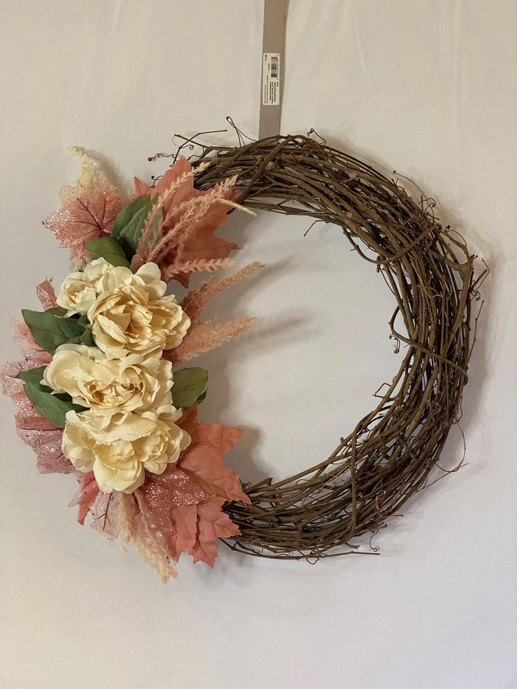 a wreath with flowers and leaves hanging on a wall