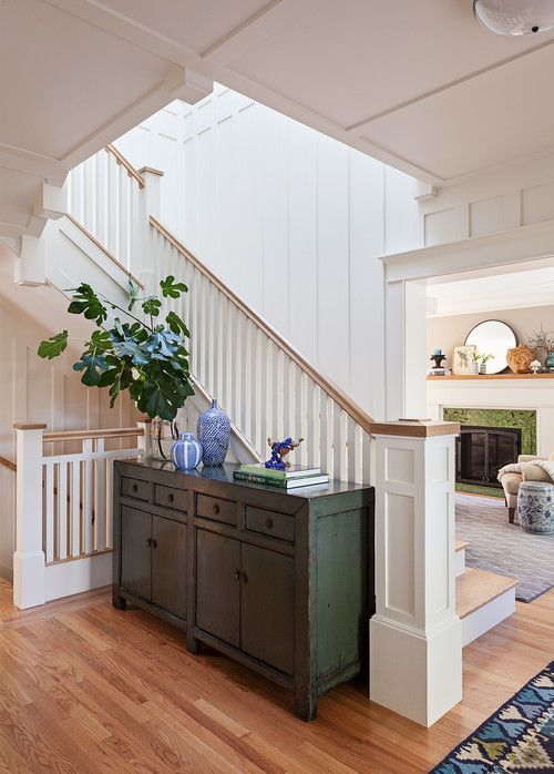 a living room filled with furniture next to a stair case on top of a hard wood floor