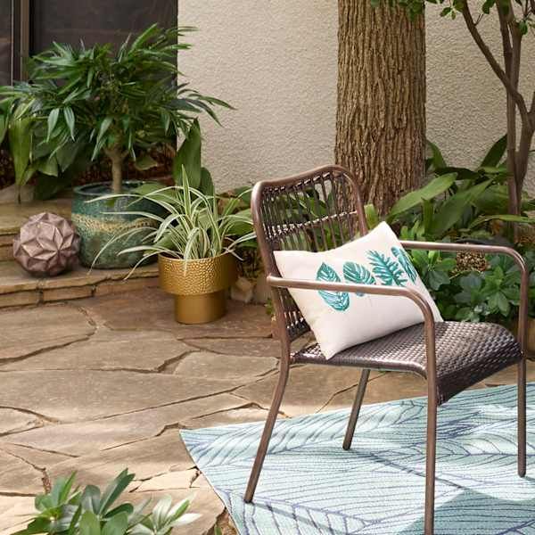 a chair sitting on top of a blue rug next to a tree and potted plants