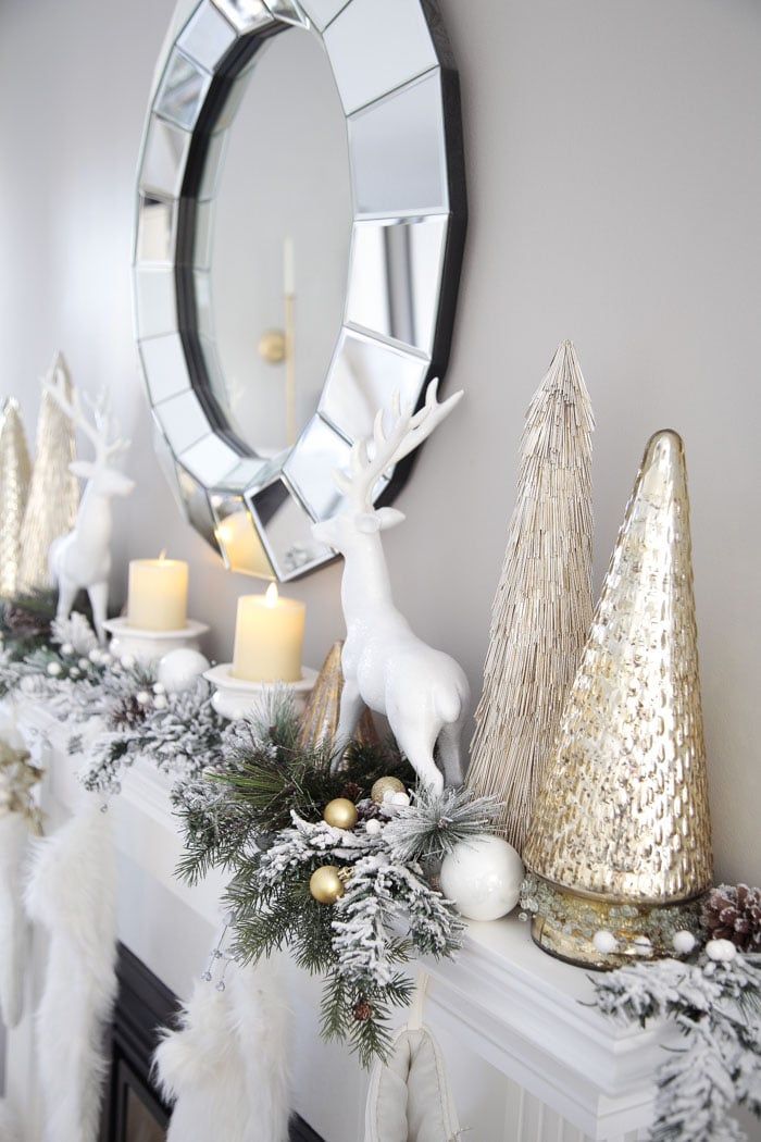 a mantel decorated for christmas with white and gold decorations