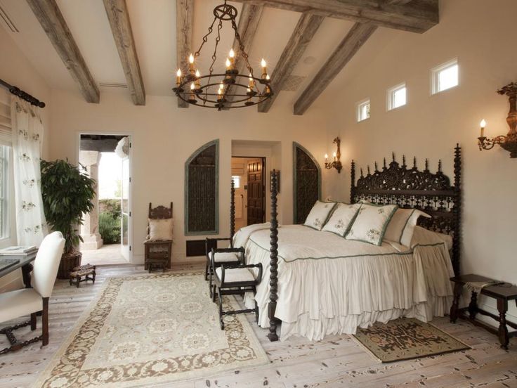 a bedroom with a large bed and chandelier hanging from the ceiling above it