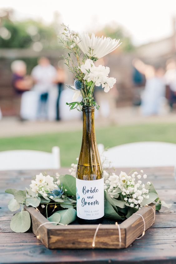 a bottle with some flowers in it sitting on a table