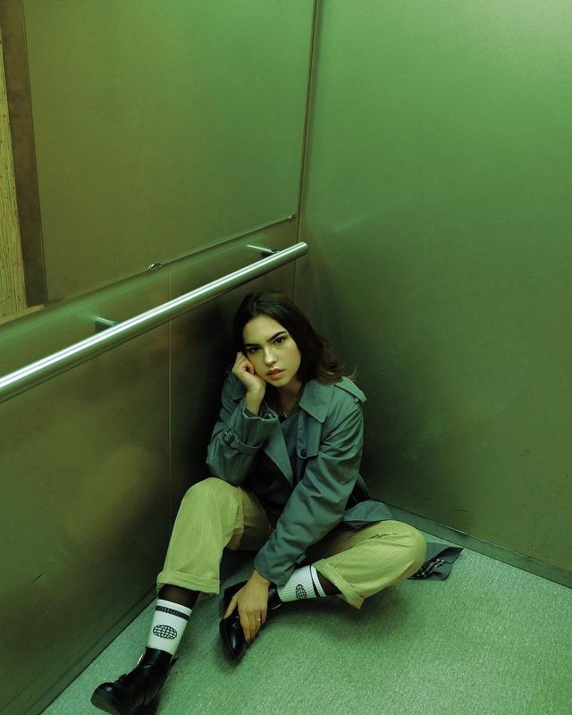 a woman is sitting on the floor in an elevator with her hand under her chin