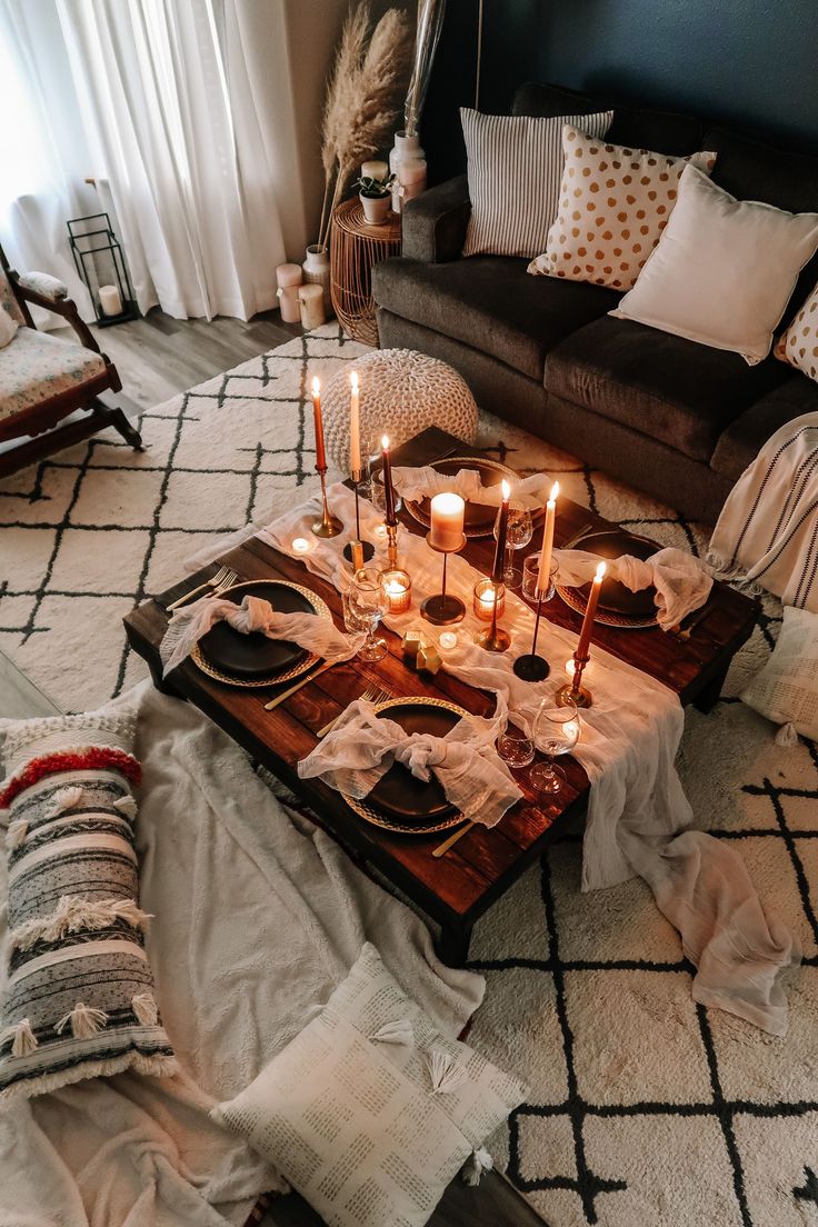 candles are lit on a tray in the middle of a living room with pillows and blankets