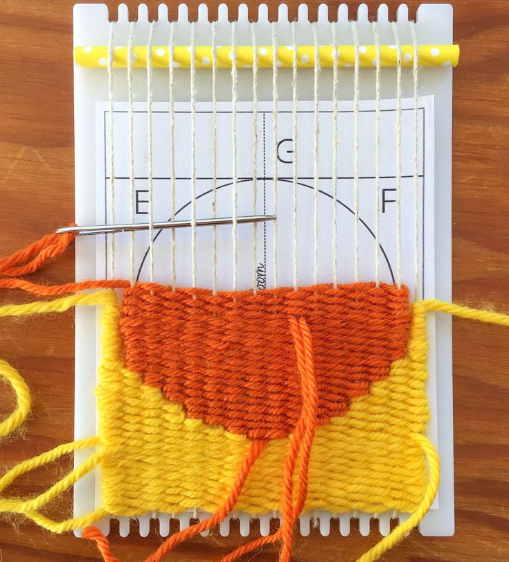 an orange and yellow piece of yarn sitting on top of a table next to a pair of scissors