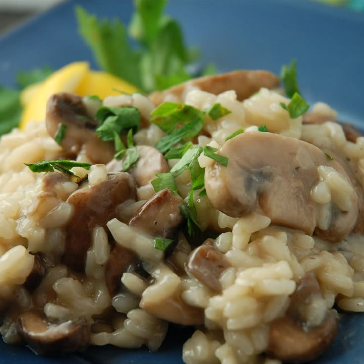 a blue plate topped with mushroom riso next to lemon wedges and parsley