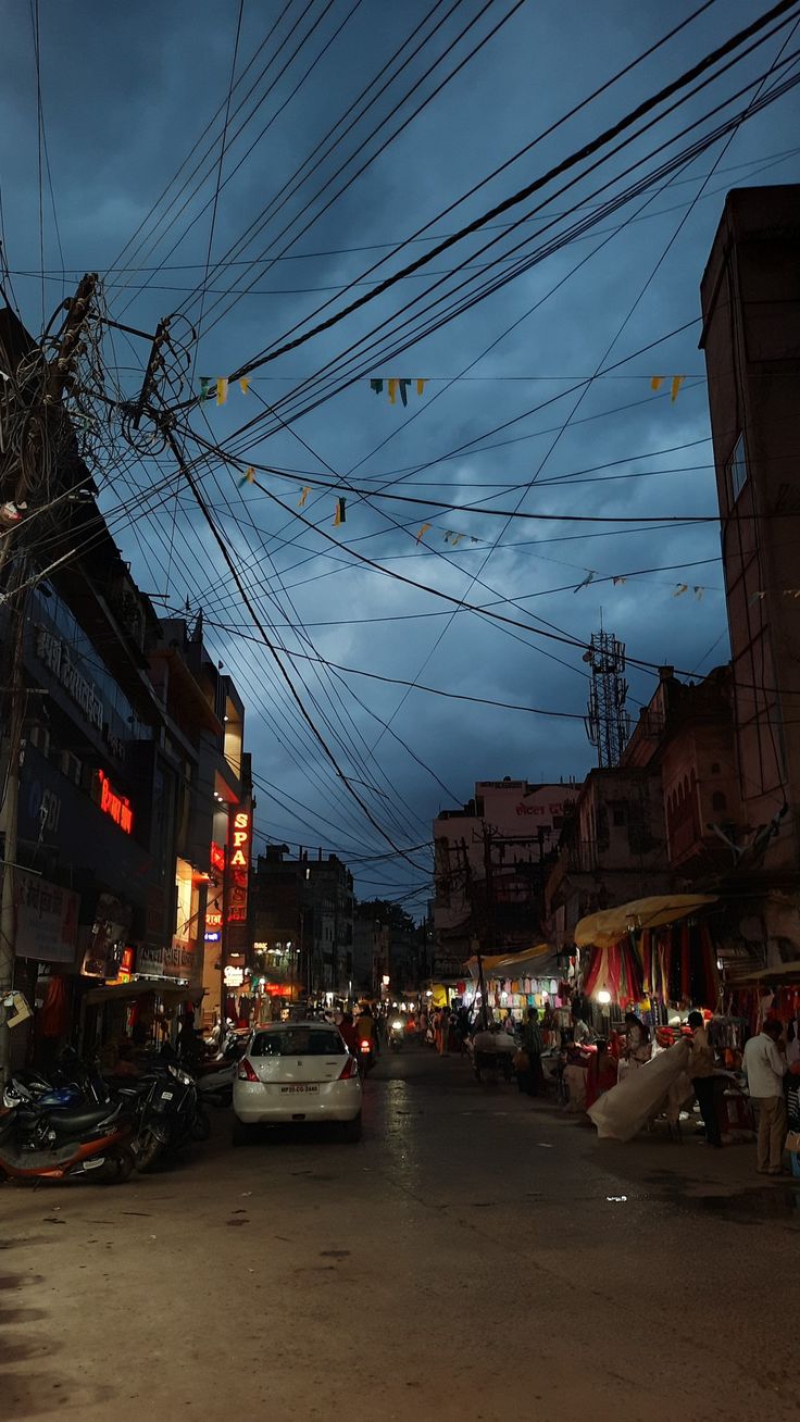 the street is crowded with cars and people on it at night, while power lines are overhead