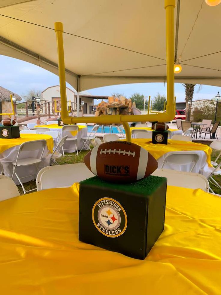 a football sitting on top of a green box under a tent next to tables with white chairs