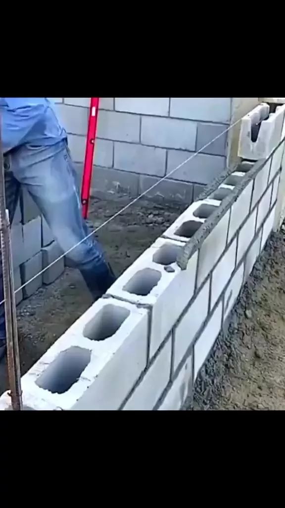 two men are working on the side of a building with concrete blocks and cement mortars