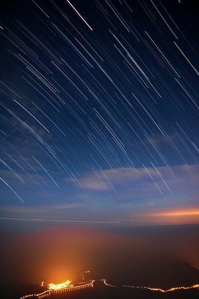 the night sky is filled with star trails and stars in the distance, as seen from an airplane