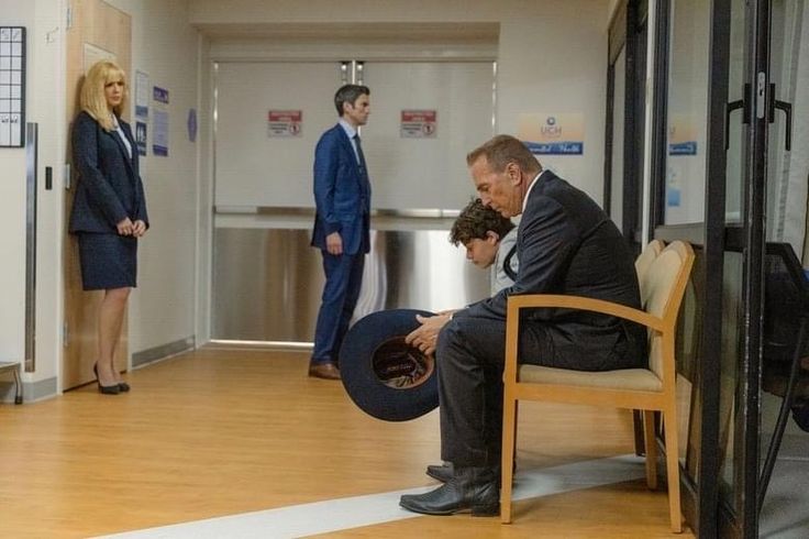 a man sitting in a chair holding a tire while two other people stand behind him