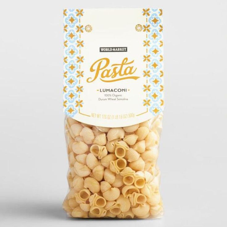 a bag of pasta sitting on top of a white countertop next to a pile of cashews