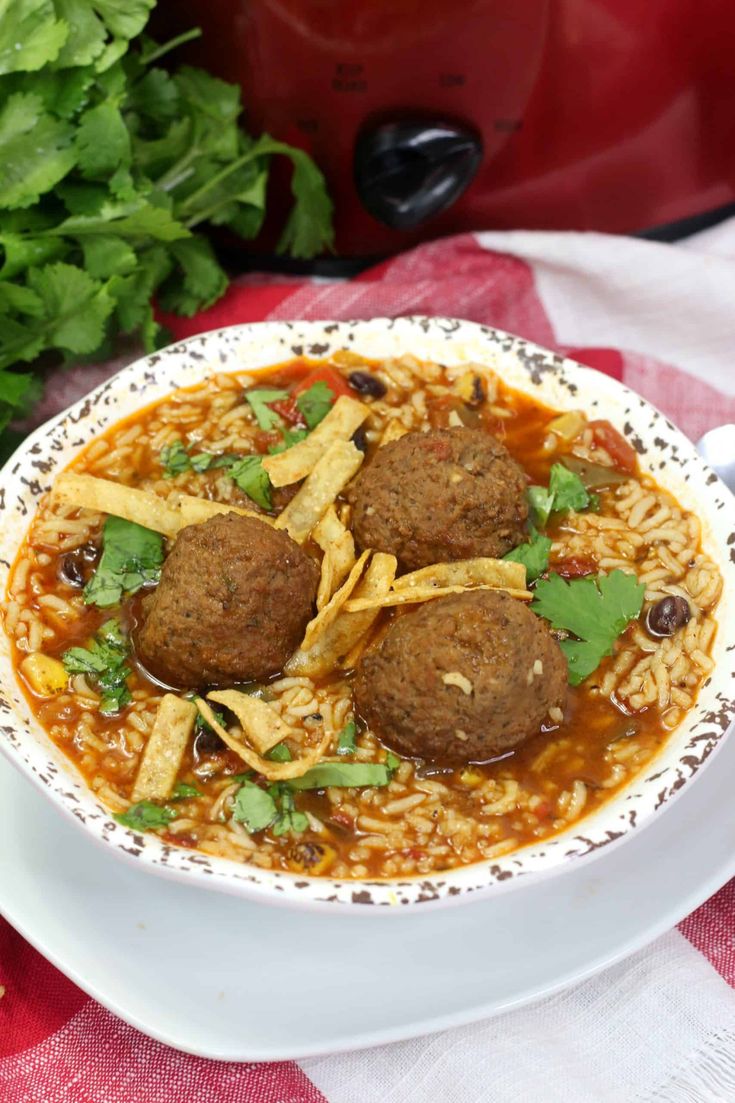 a white bowl filled with meatball soup and tortilla chips on top of it