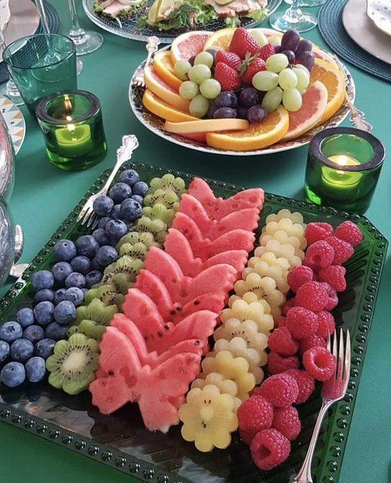 a table topped with plates of fruit and watermelon cut in half to look like animals