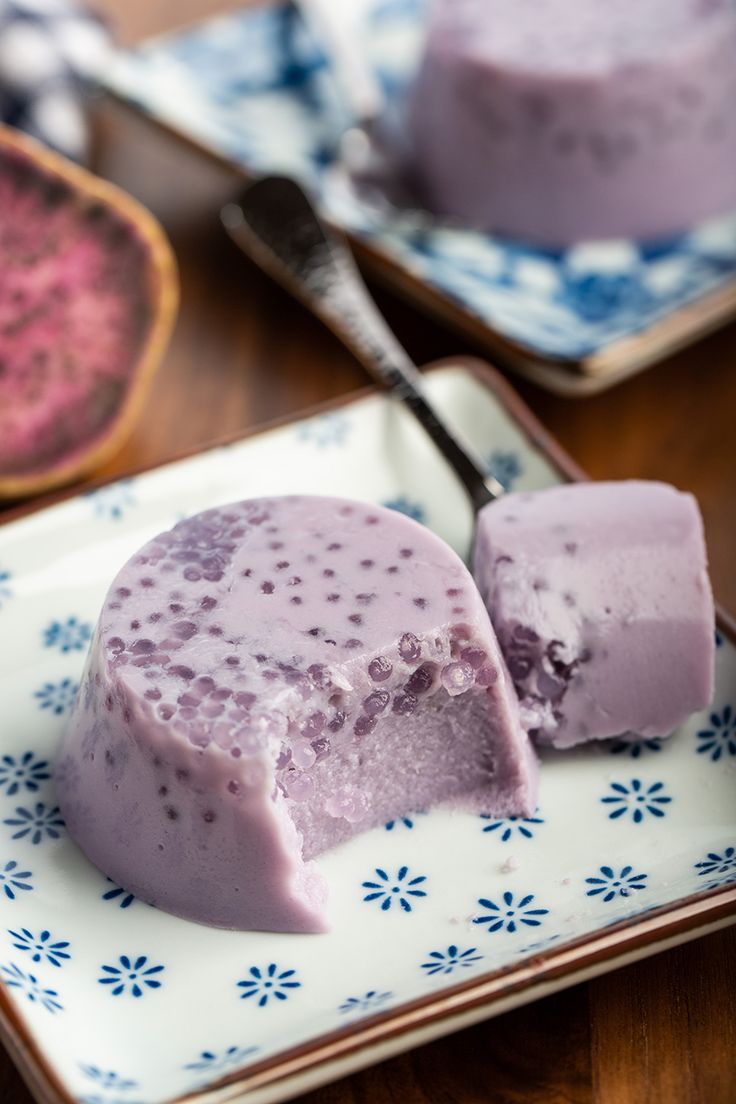 two pieces of ice cream sitting on top of a blue and white plate next to a spoon