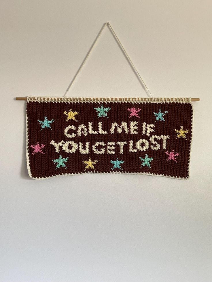 a knitted sign hanging on a wall that says, calm me you get lost