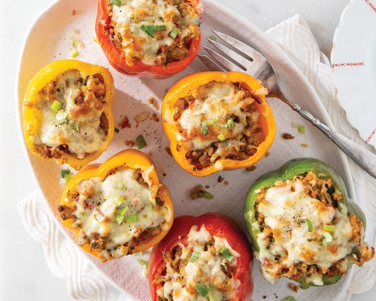 four stuffed peppers on a plate with a fork