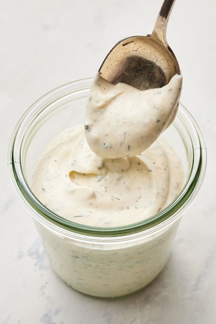 a spoon full of mayonnaise sitting in a jar