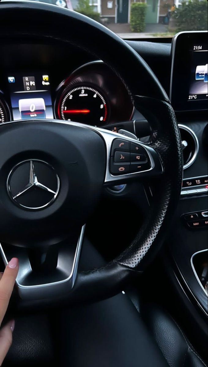 a person driving a car with their hand on the steering wheel and dashboard screen showing