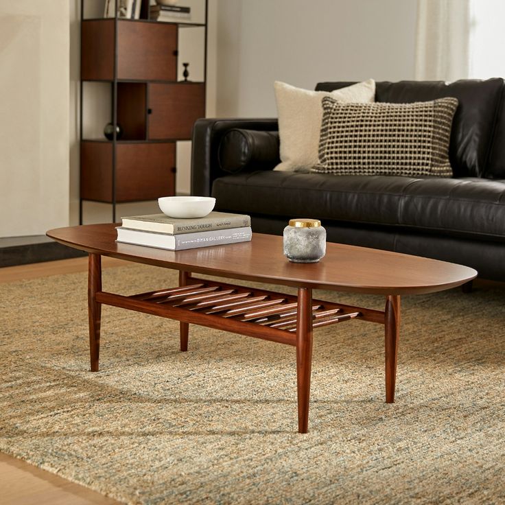 a living room with a couch, coffee table and books on the floor in front of it