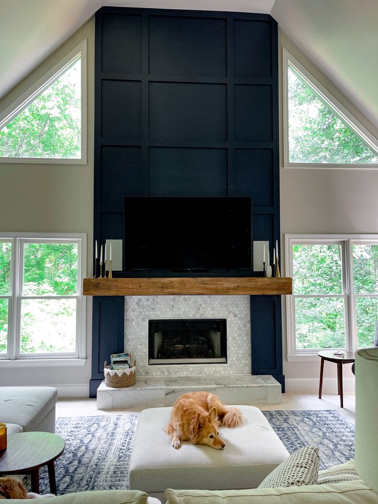 a living room with a large fireplace and lots of windows in it's walls