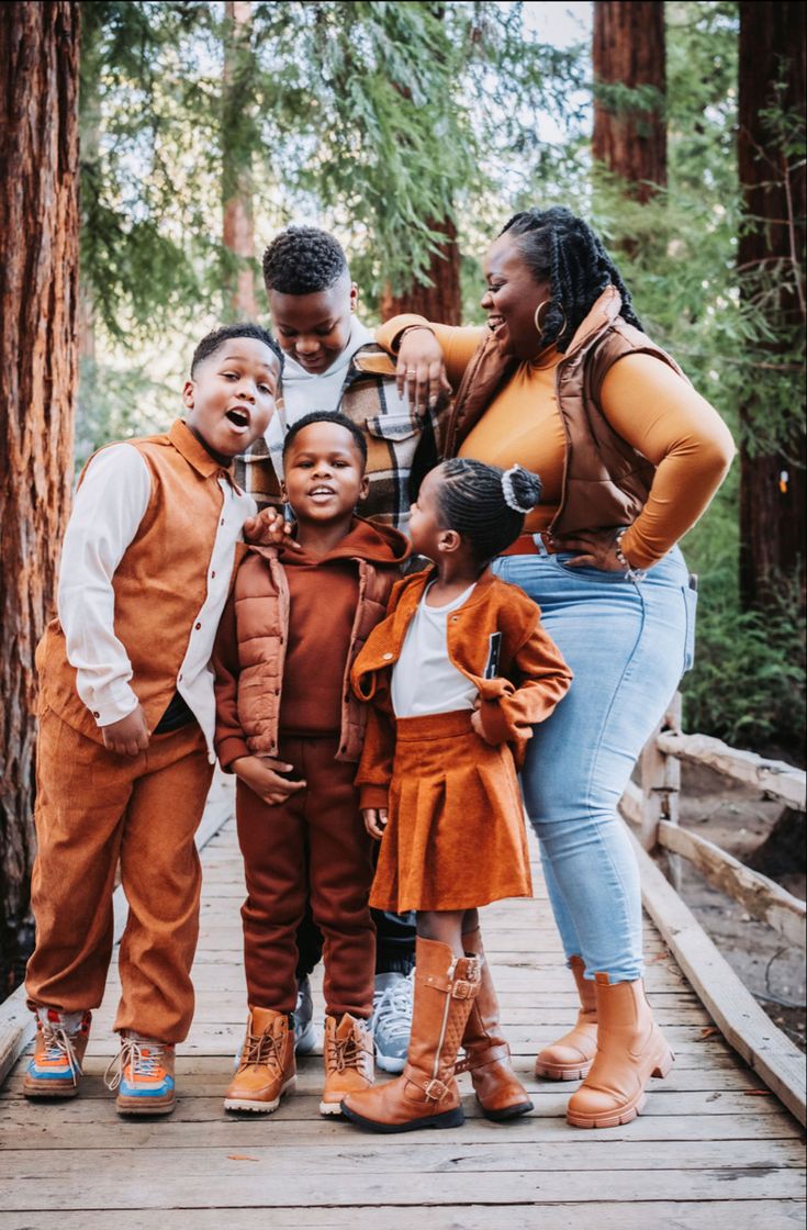 a group of children standing on a wooden bridge in the woods with their mom and dad