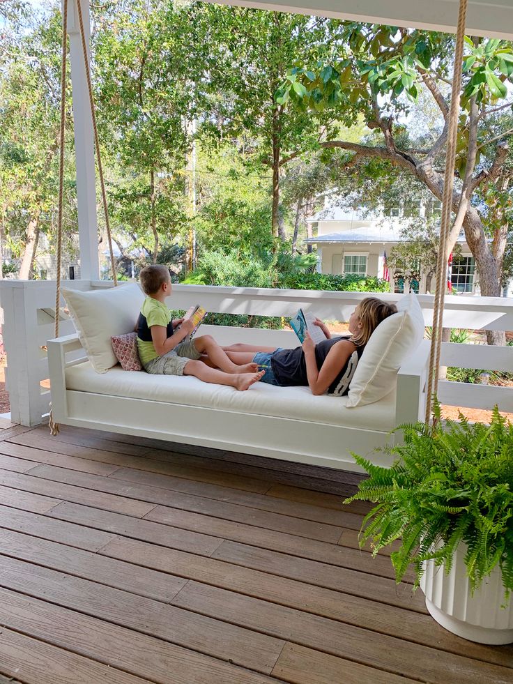 two children sitting on a porch swing reading