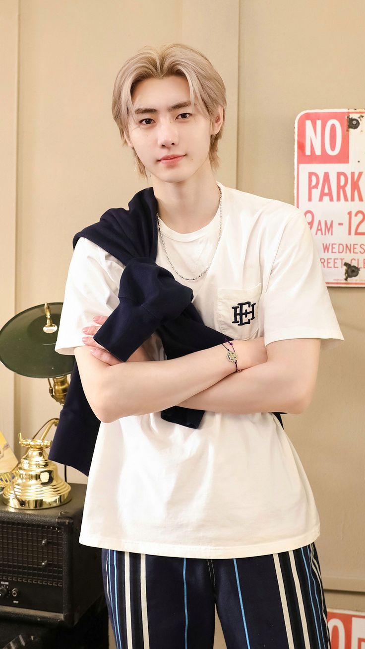 a young man standing in front of a no parking sign with his arms folded up