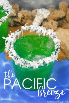 two glasses filled with green drinks sitting on top of a blue table