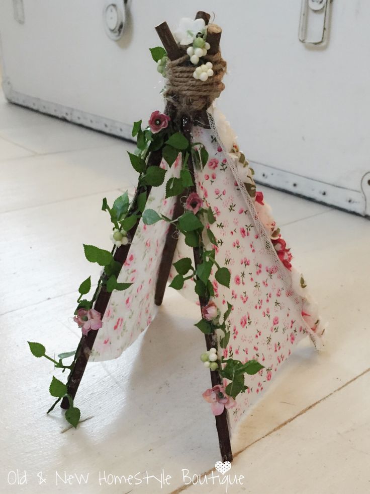 a small teepee decorated with flowers and greenery is sitting on the floor next to a suitcase