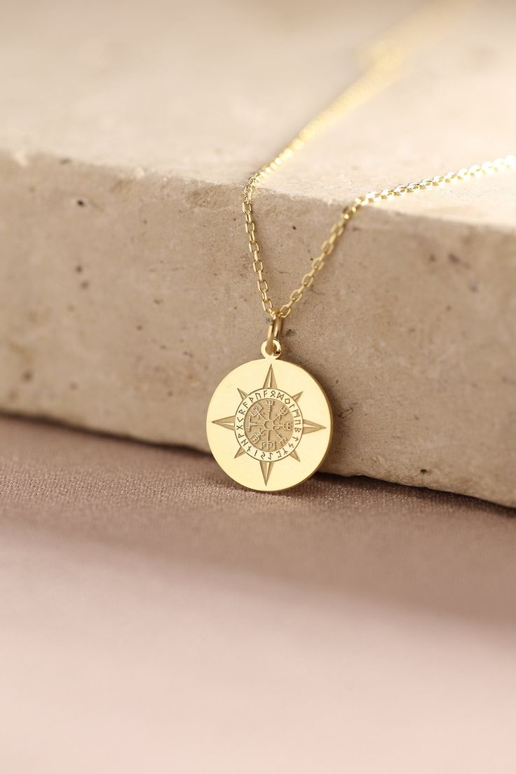 a gold necklace with a compass on it