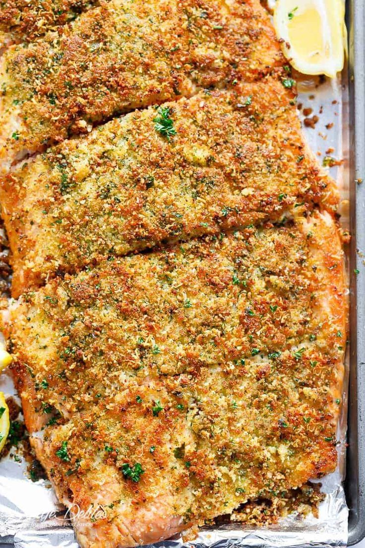 baked fish fillets in a pan with lemons and parsley on the side