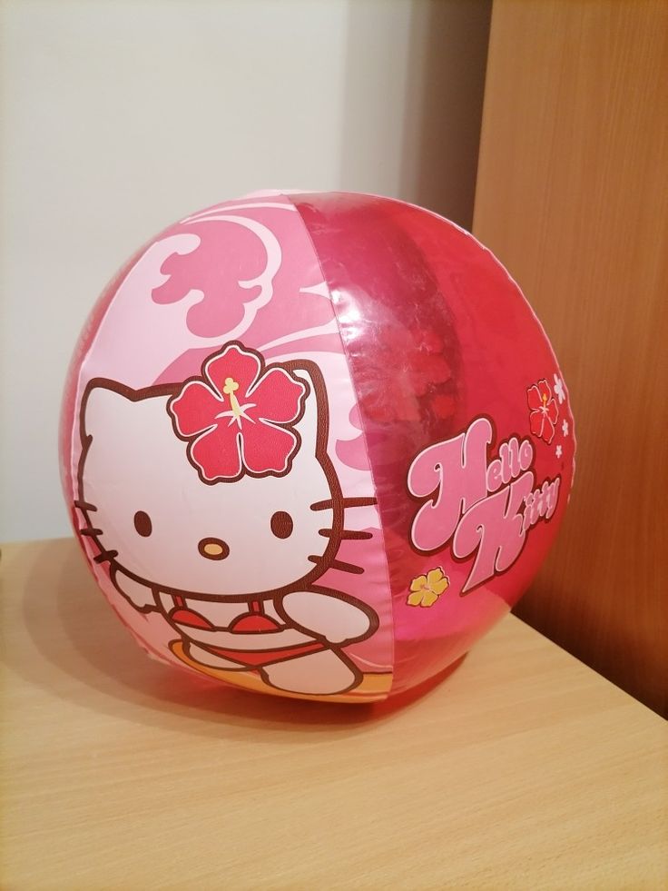 a pink hello kitty ball sitting on top of a wooden table next to a wall