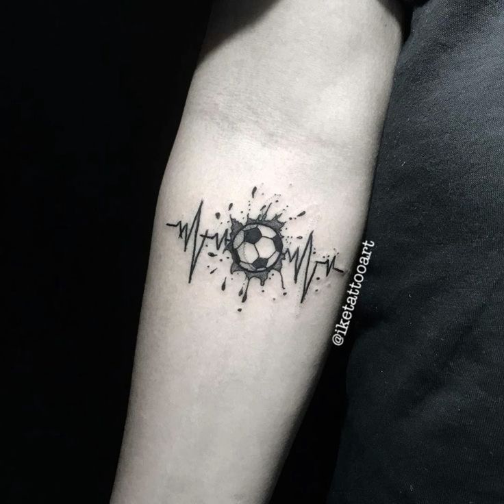 a black and white photo of a person with a heartbeat tattoo on their arm that has a soccer ball in it