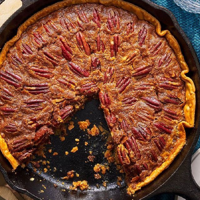 a pecan pie in a cast iron skillet with one slice missing from it