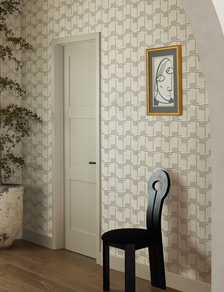 a black chair sitting in front of a white door next to a potted plant