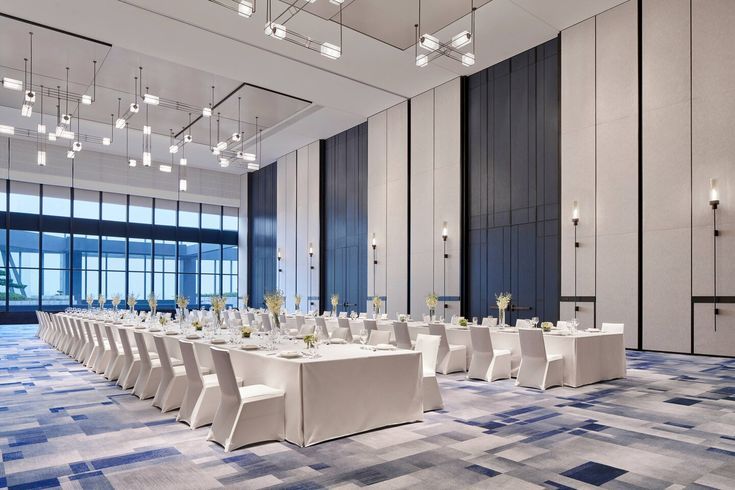 a banquet hall with tables and chairs set up for a formal function in front of large windows