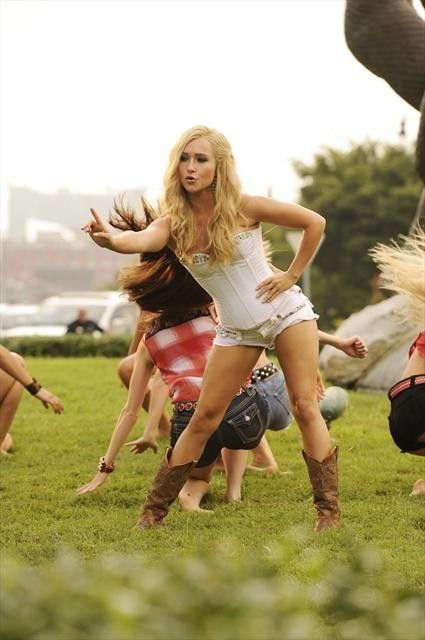 two women in short shorts and cowboy boots are dancing