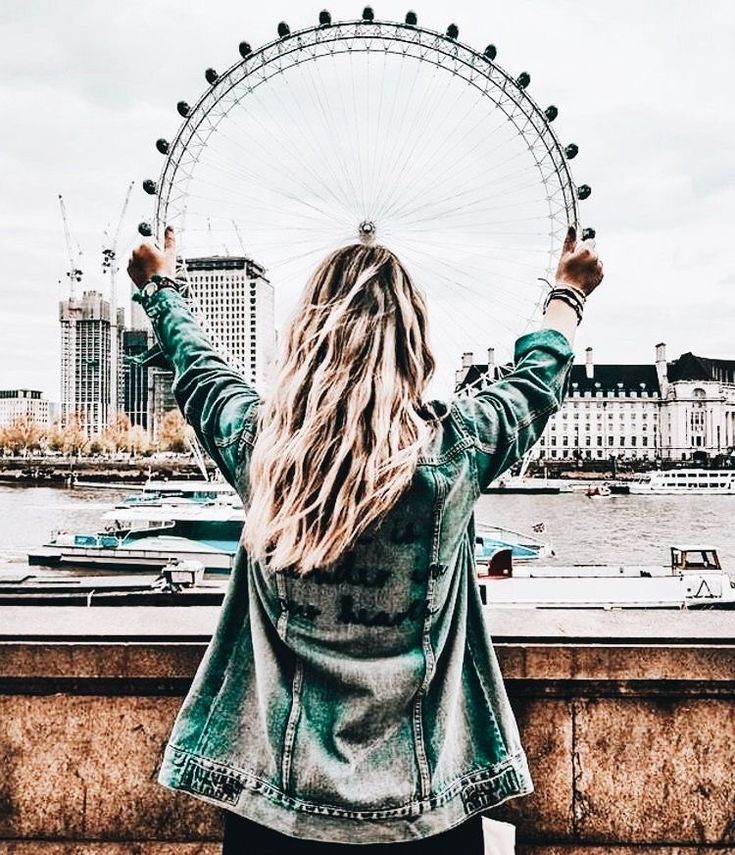 a woman standing in front of a ferris wheel with her arms up and hands raised