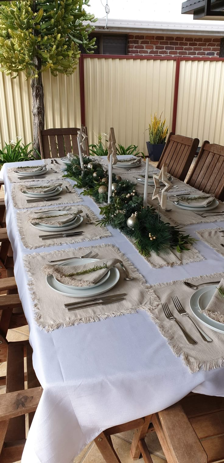 the table is set with place settings for six to eight people, and has pine cones on them