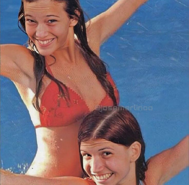 two young women in bikinis are posing for a photo by the swimming pool with their arms outstretched