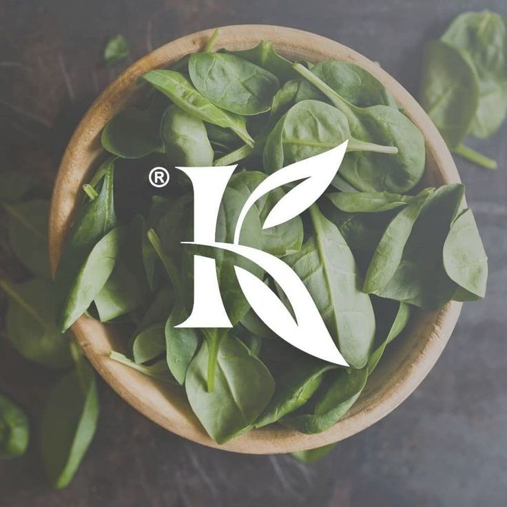 a wooden bowl filled with green leaves