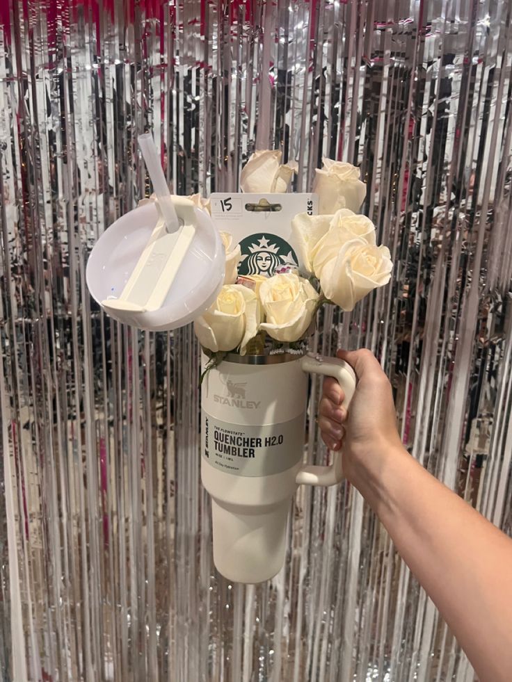 a starbucks cup with flowers in it being held up by someone's hand,