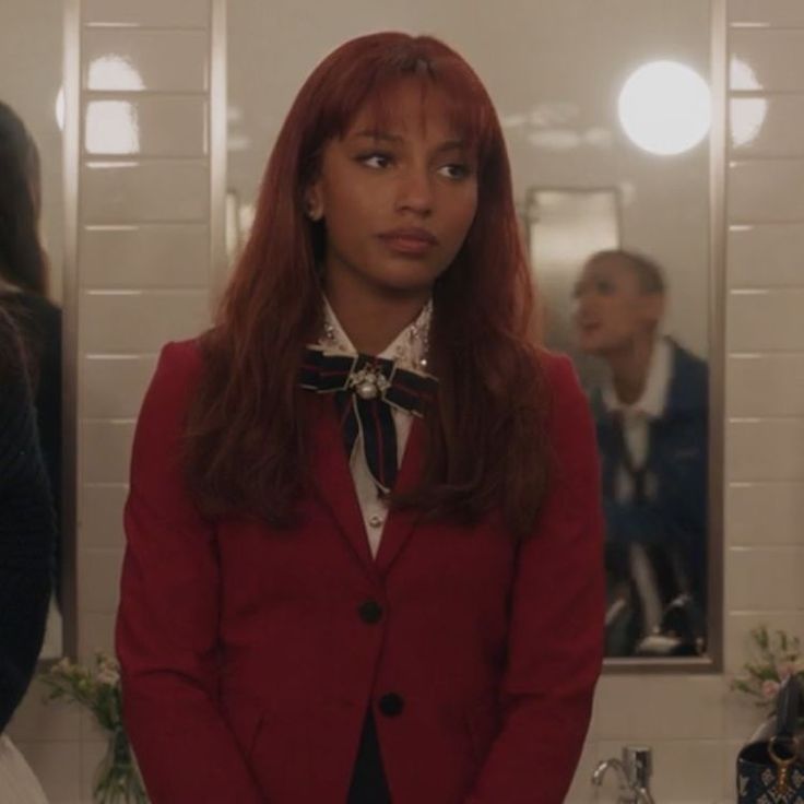 a woman standing in front of a mirror wearing a red blazer and bow tie